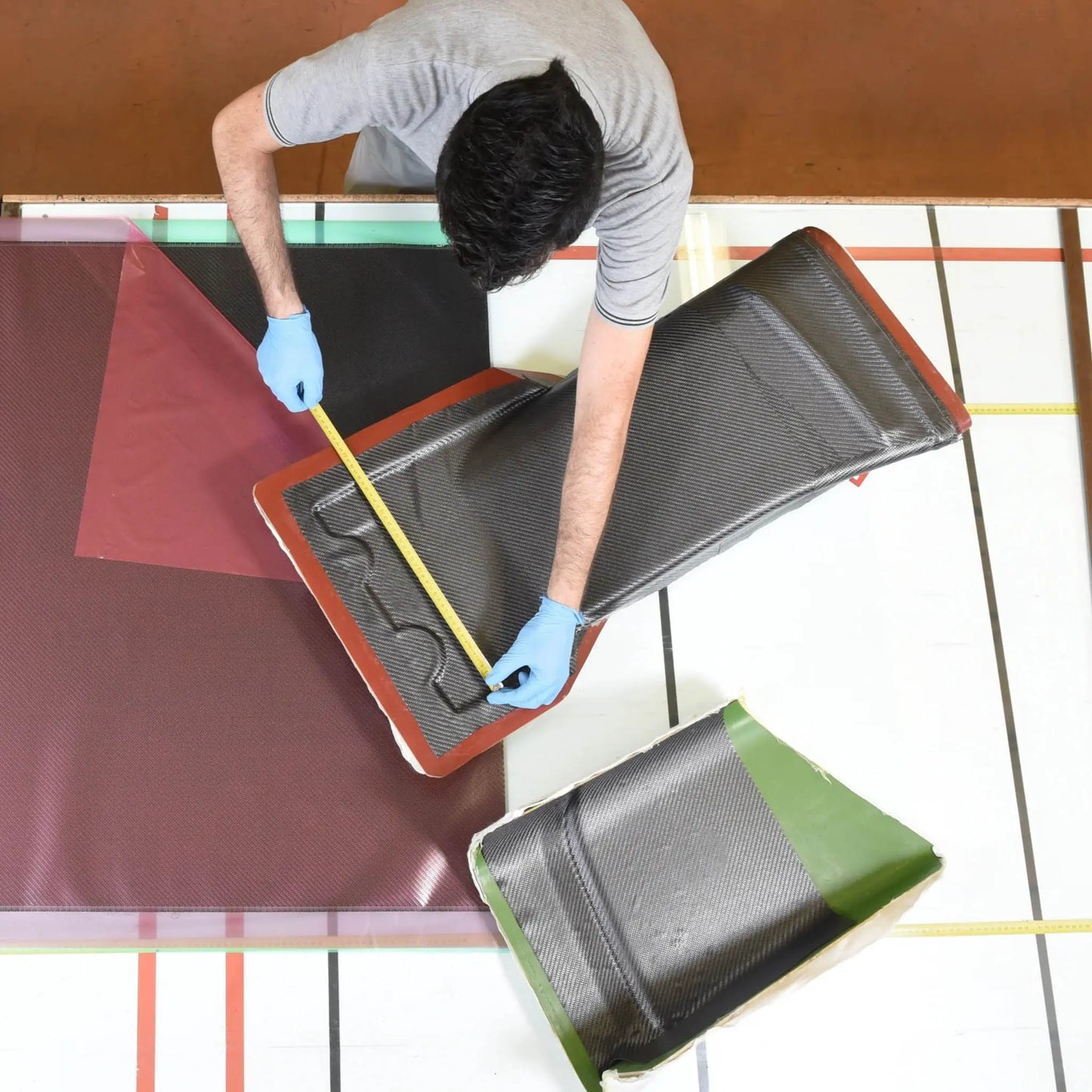 Technician measuring prepreg carbon fibre during a hands-on composites training course in the UK, demonstrating accurate lay-up preparation.