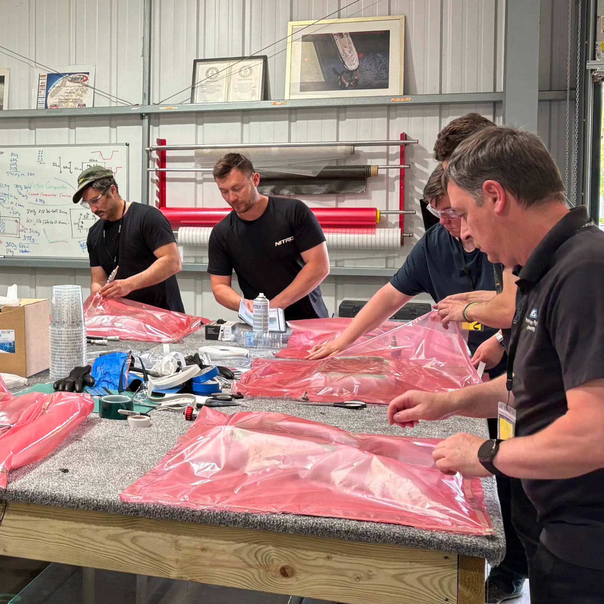 Students learning carbon fibre manufacturing techniques on a hands-on UK training course, working together on composite lay-up and vacuum bagging.