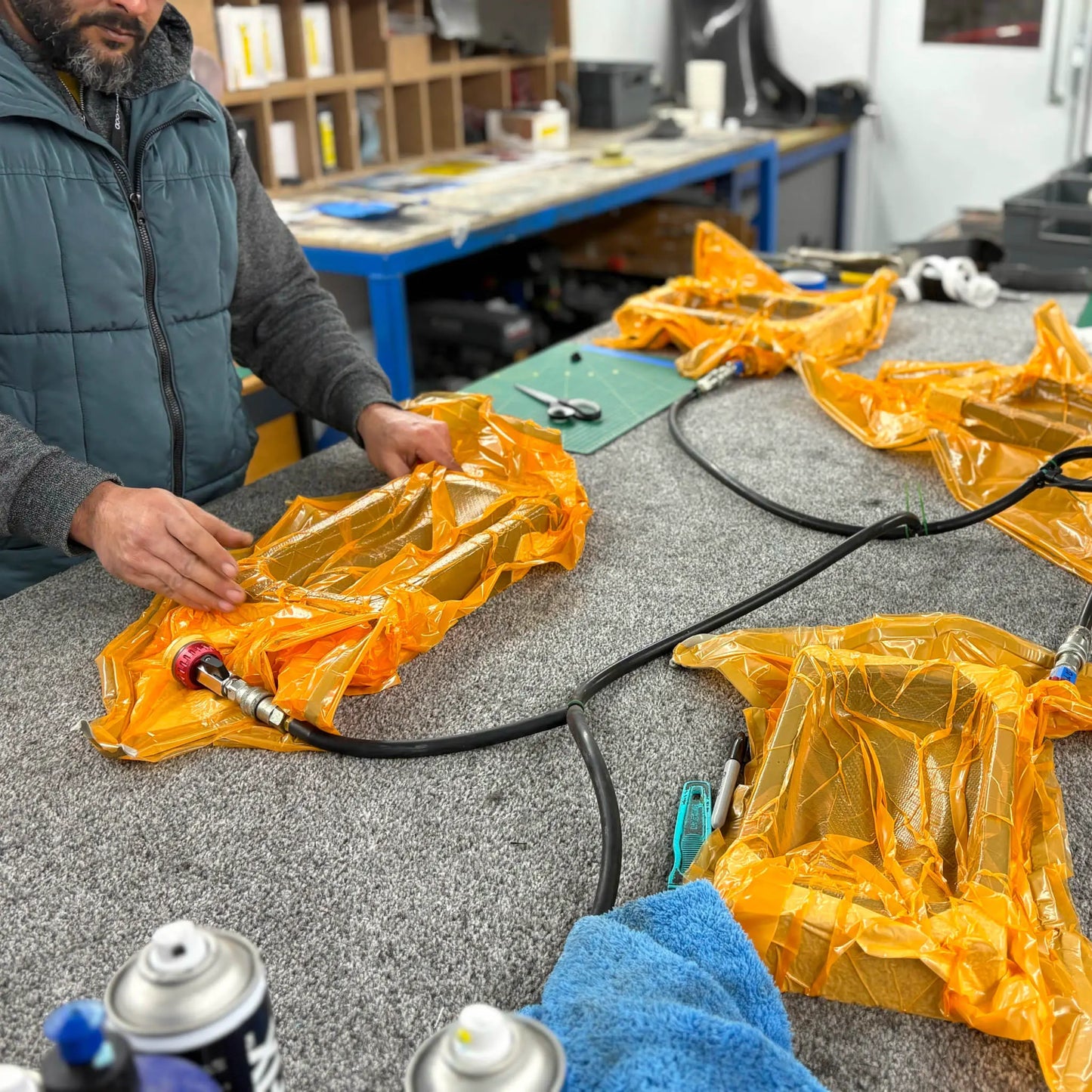 Vacuum resin infusion process being demonstrated during an advanced carbon fibre training course, showing sealed composite parts on a workshop bench.